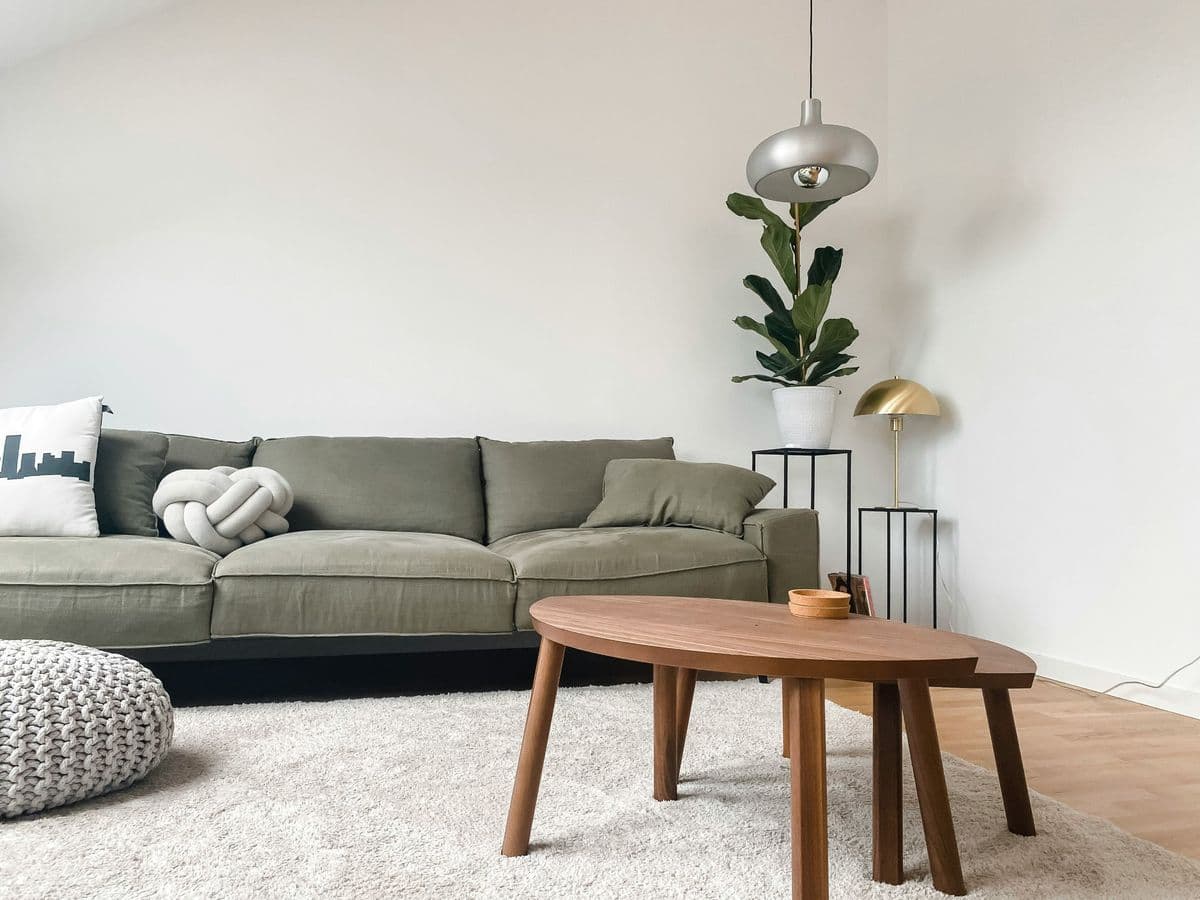 Ruang keluarga Japandi dengan sofa hijau dan meja kayu